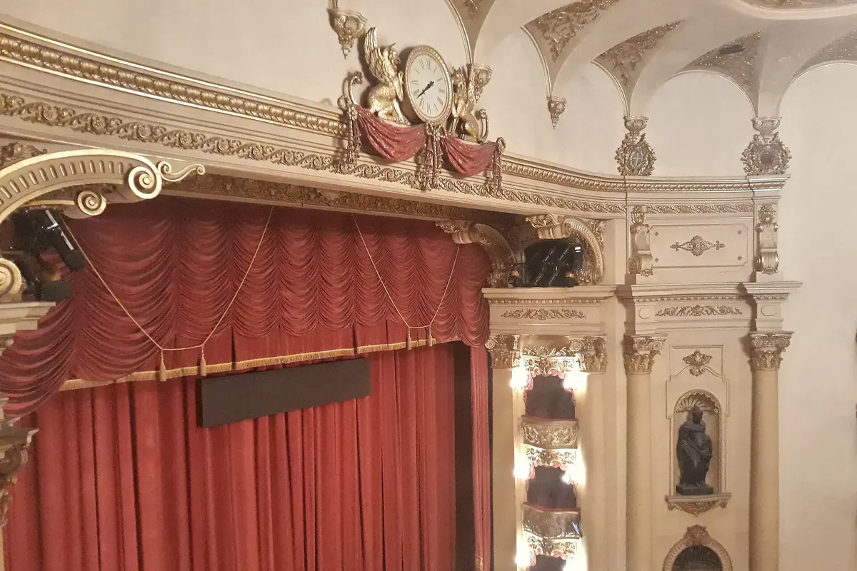 Die Bühne des Teatro Filarmonico, ein roter Vorhang unter einem prunkvollen creme- und goldfarbenen Bogen